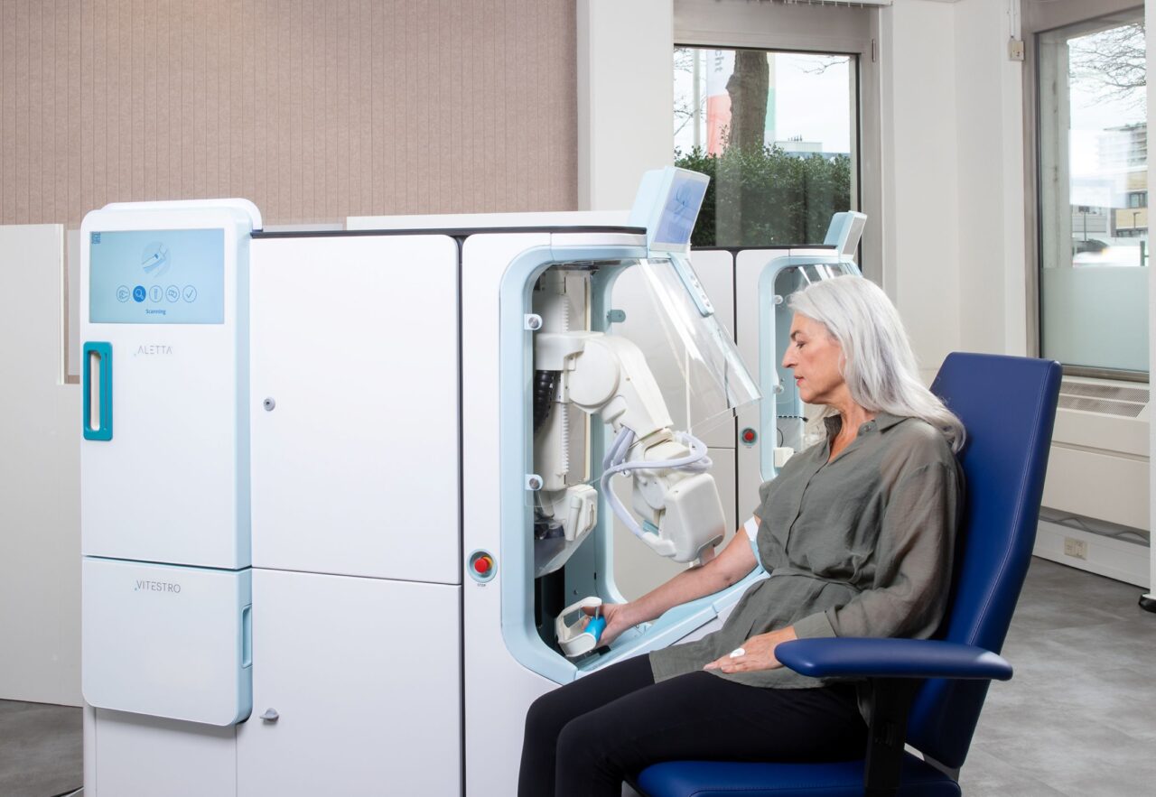 Patient utilisant le dispositif robotique Aletta de Vitestro pour une prise de sang supervisée