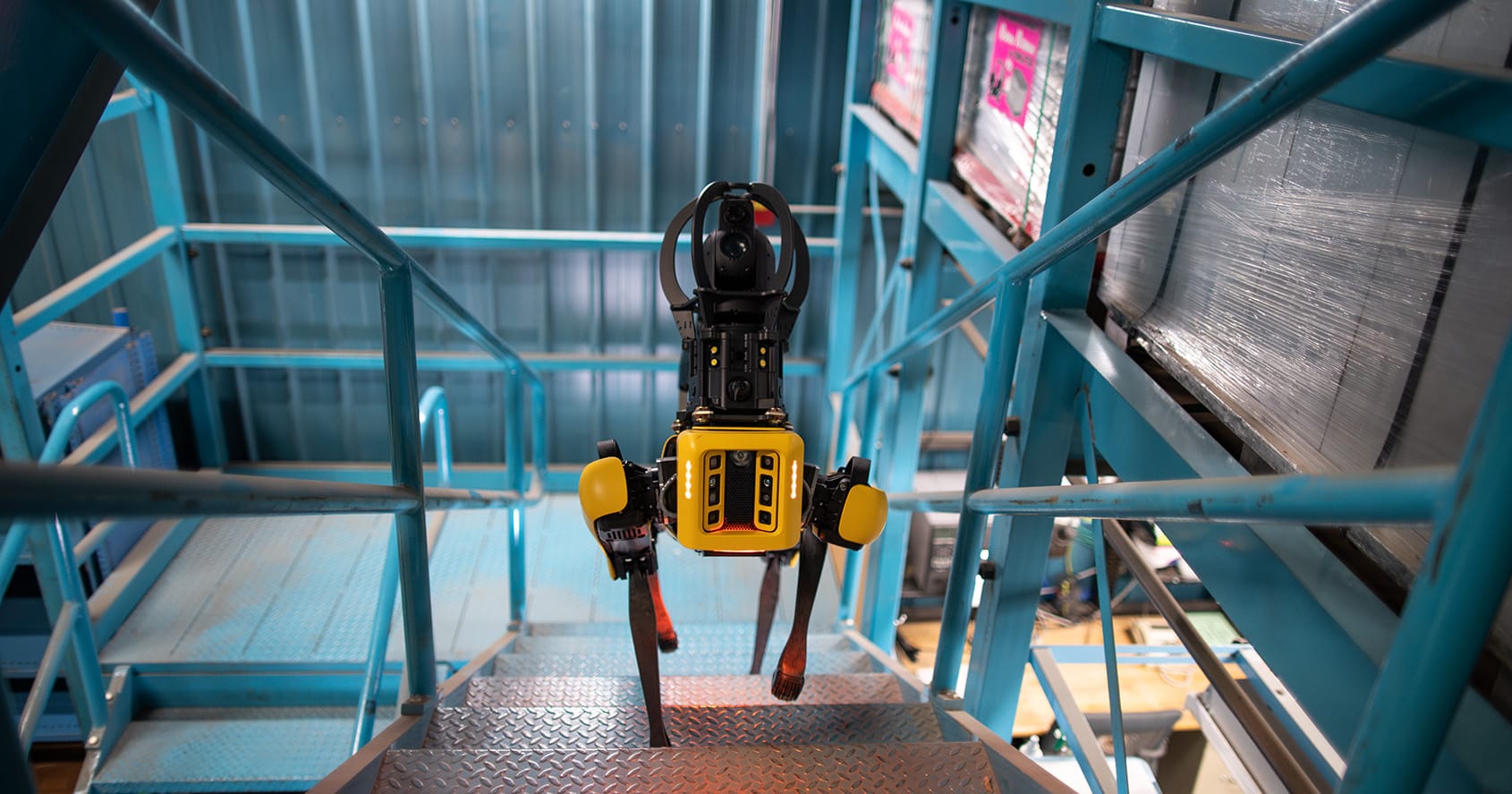 Robot quadrupède Spot de Boston Dynamics montant un escalier dans une installation industrielle