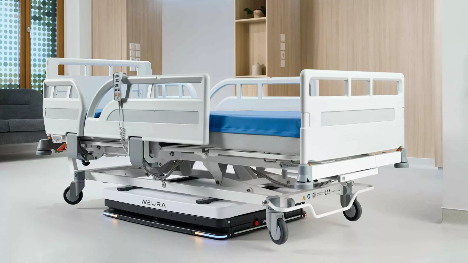 Robot mobile autonome Neura soulevant un lit vide dans une chambre d’hôpital