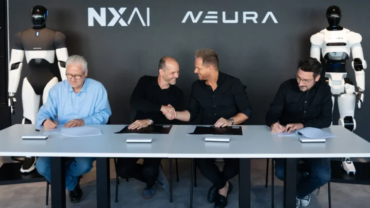 Équipes de NEURA Robotics et NXAI signant leur partenariat devant deux robots humanoïdes