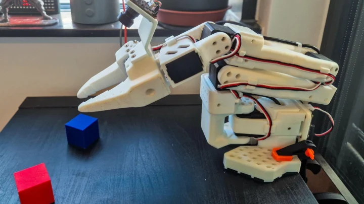 Bras robotique SO-101 équipé d’une caméra au poignet devant des cubes rouges et bleus
