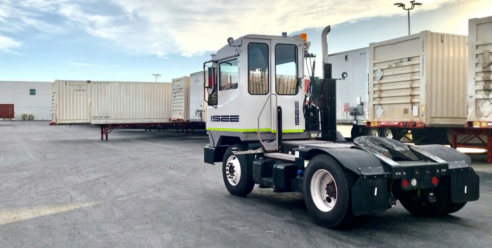 Deux camions de parc autonomes ISEE devant des remorques logistiques
